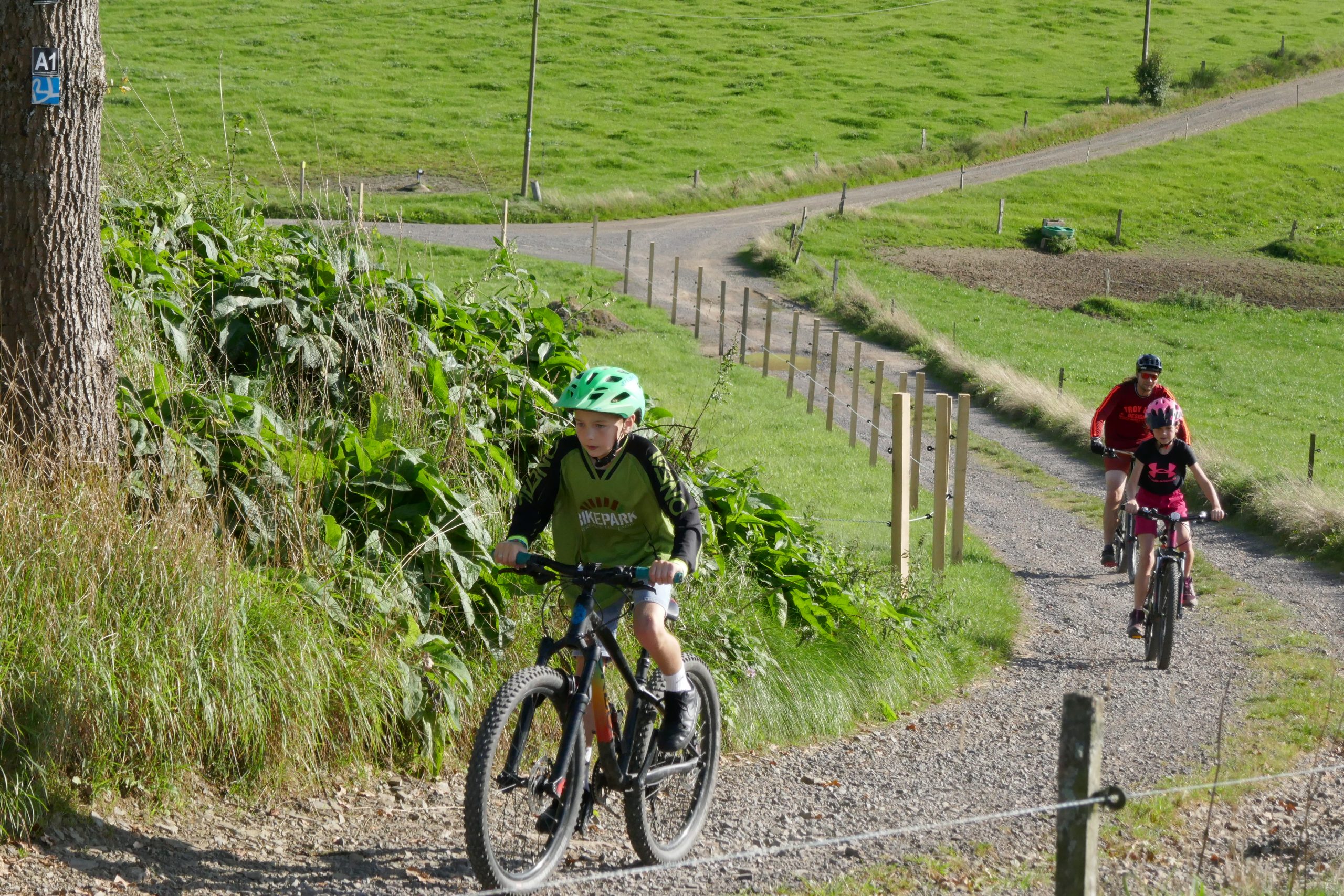 Junge auf Mountainbike mit zwei Personen auf Mountainbikes im Hintergrund